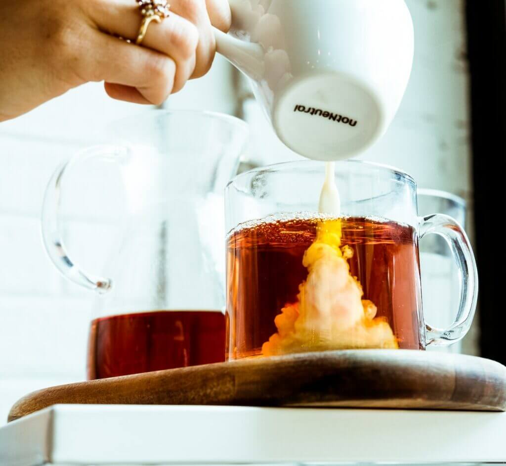 person pouring milk in tea